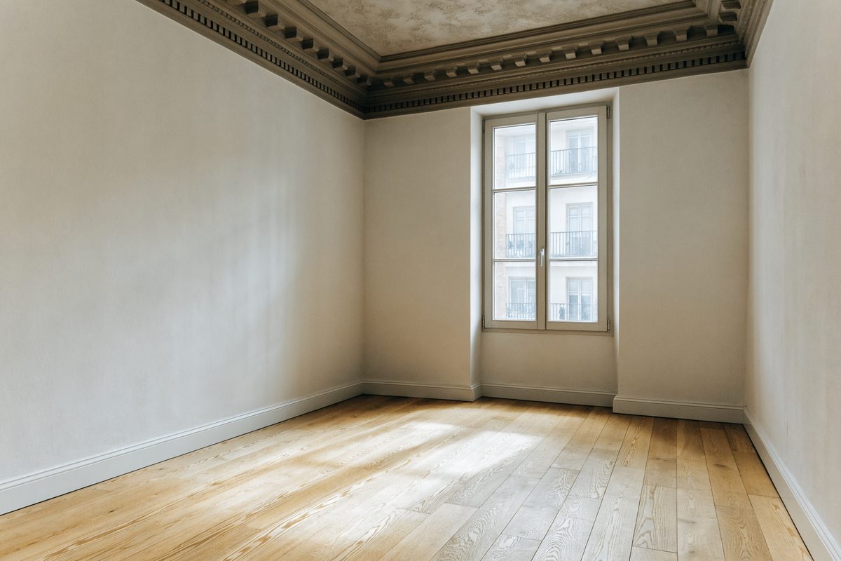 Leerer, fertig sanierter Wohnraum mit weißen Wänden und neu verlegtem Boden